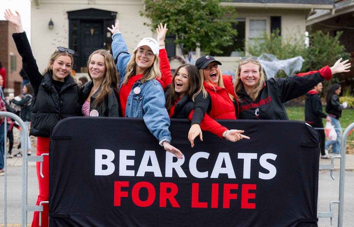 Group of alumni at the Homecoming 2025 Parade behind a 'Bearcats for Life' bike rack